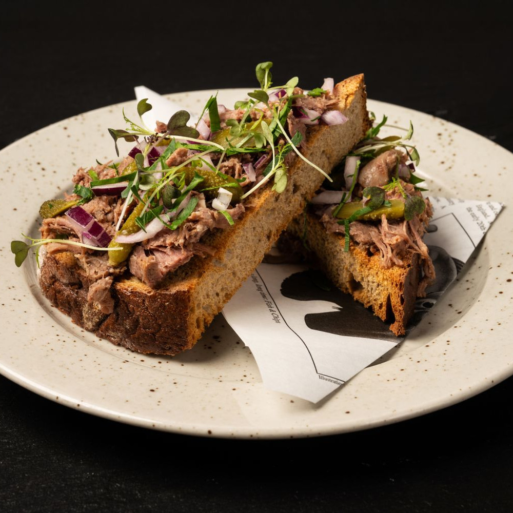 Hovězí trhané podávané za studena na opečeném dvoukváskovém chlebu, nakládané okurky, cibulka