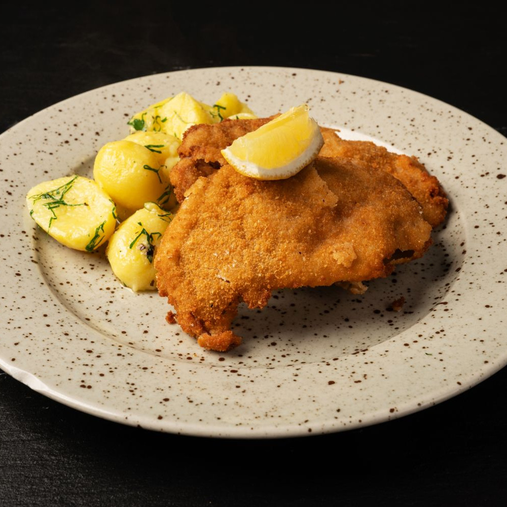 Smažený česnekový řízek z vepř. panenky podávané s vařeným bramborem na bylinkovém másle